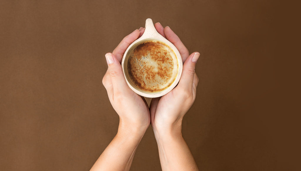 Hands holding a coffee cup filled with flow brew